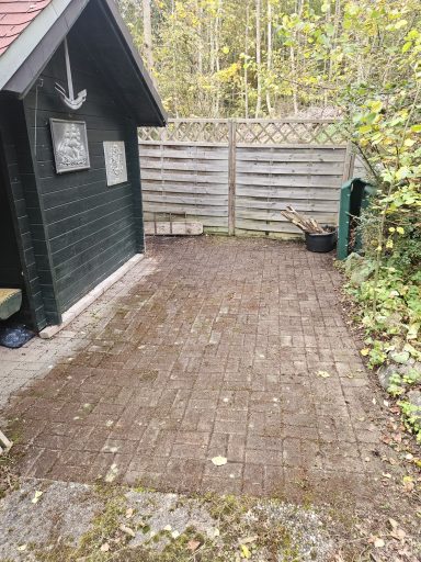 Objekt Nr.1 Gartenhaus-Bereich - VS-Marbach Pflasterweg vor einer Holzhütte, umgeben von Bäumen und einem Zaun.